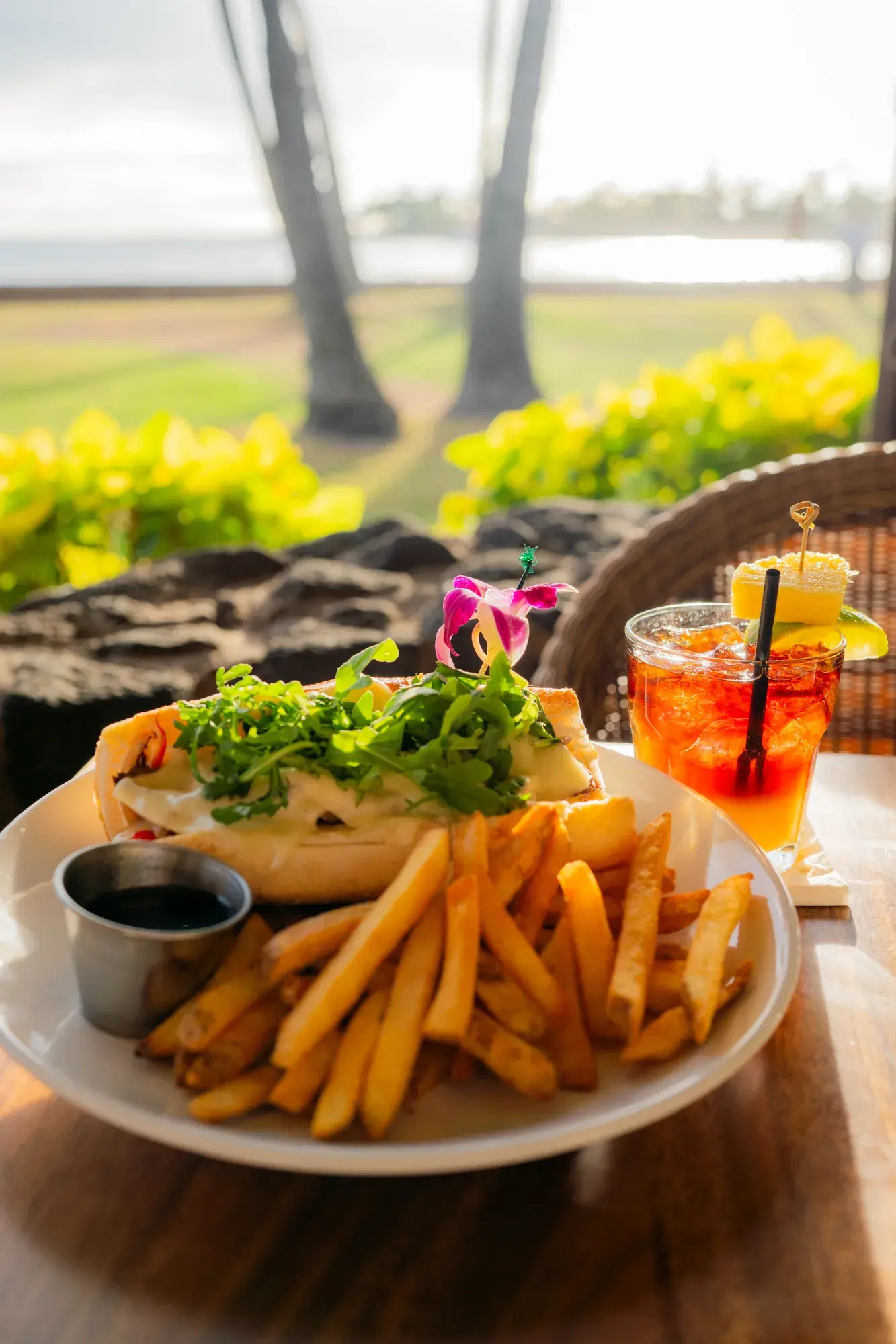 Prime Rib Sandwich at Kona Inn Restaurant, Caramelized onion, bell pepper, Swiss cheese, creamy horseradish, roasted prime rib, arugula, hoagie roll, au jus, with French fries.