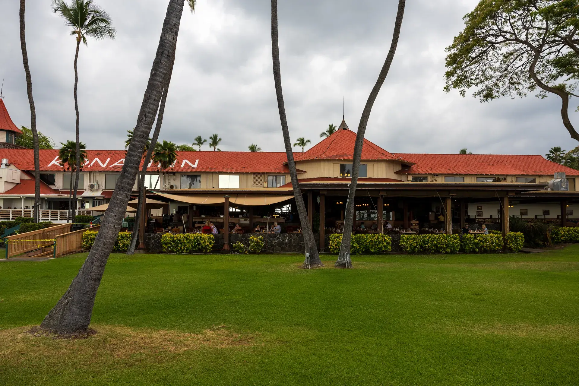 Kona Inn Restaurant seen across the waterfront lawn with its red roof and palm trees in Kailua-Kona