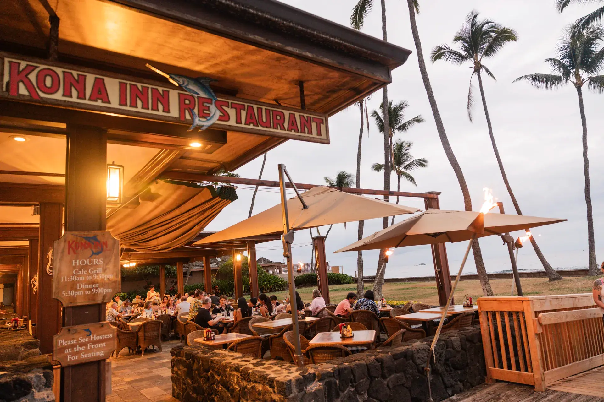 Open-air oceanfront dining on the lanai at Kona Inn Restaurant at dusk, right on the water on Aliʻi Drive